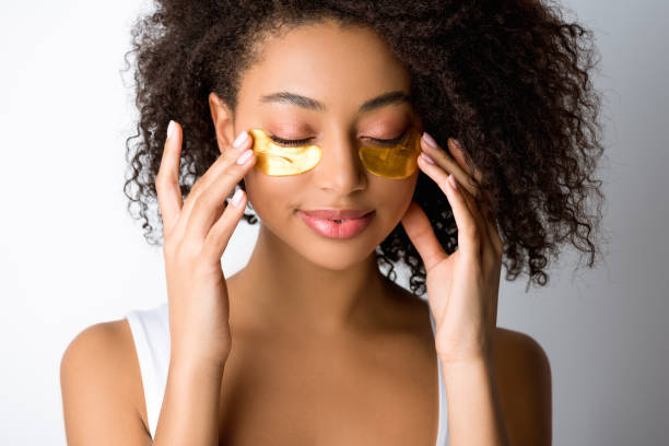 attractive smiling african american girl with golden eye patches, isolated on grey
